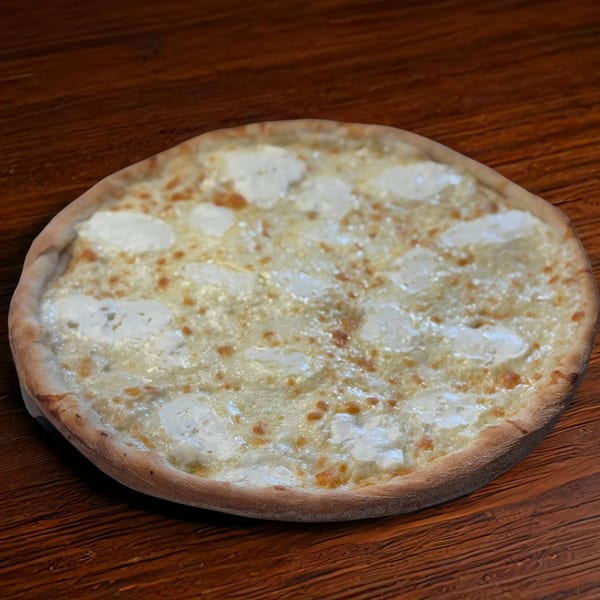 NYC Village Pizza's white pizza with melted mozzarella and ricotta cheese on a wooden table.
